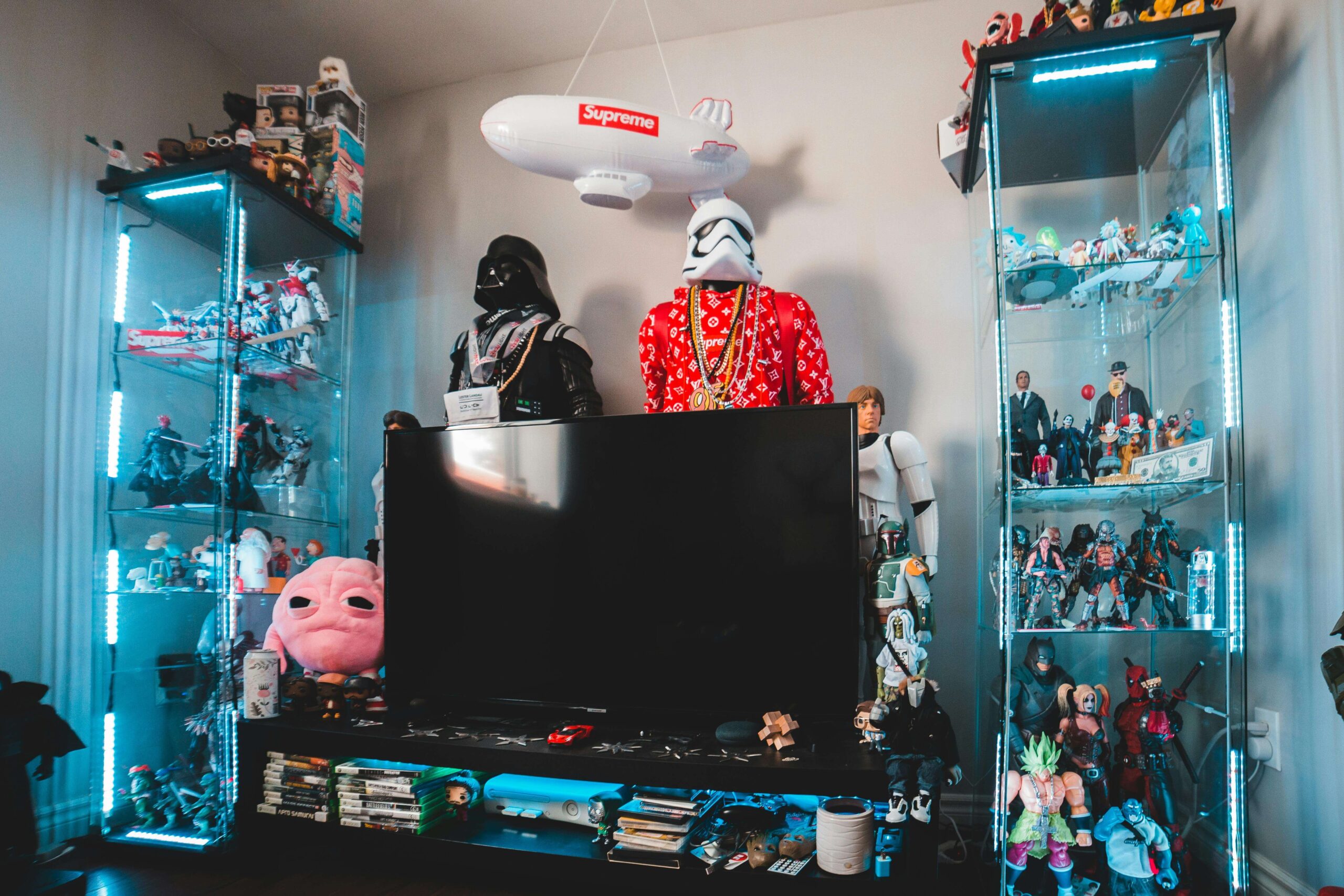 "Coleção de action figures geeks premium em estante iluminada" "Hot Toys Iron Man Mark 85 em pose heroica" "Funko Pop raros e chase variants em display" "Batmóvel 1989 escala 1:18 com portas abertas" "Sabre de luz Black Series com LED ativado"